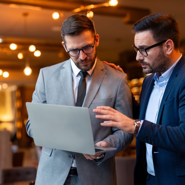 Two businesspeople having a discussion with their clients during an online meeting. Modern businessmen having a video conference in a co-working office.